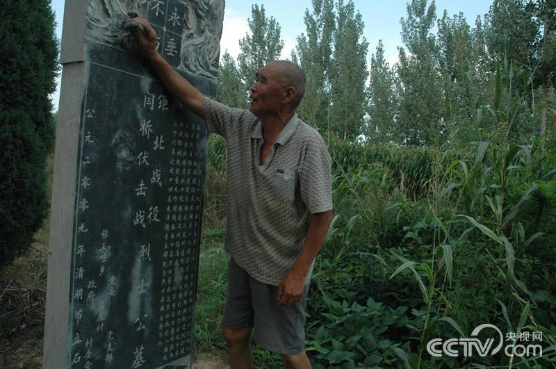 苗明文在擦拭“八路墳”墓碑上的塵土